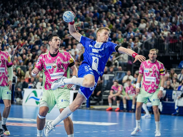 VFL GUMMERSBACH vs. Füchse Berlin A VfL Gummersbach handball player taking a jump shot against the Füchse Berlin in a packed arena