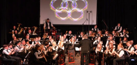 Bigband-Orchester mit Dirigent auf Bühne, Projektion aus farbigen Ringen im Hintergrund