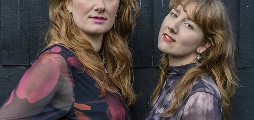 Porträt der Rheingans Sisters vor dunkler Holzwand
