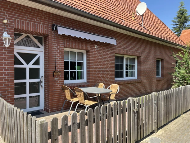 Bakstenen huis met terras, zitje en houten schutting voor de vakantiewoning.