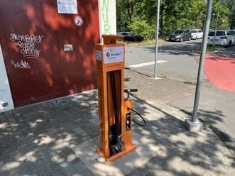 Orange Fahrradreparaturstation mit Luftpumpe an der BBS Verden neben Straße.