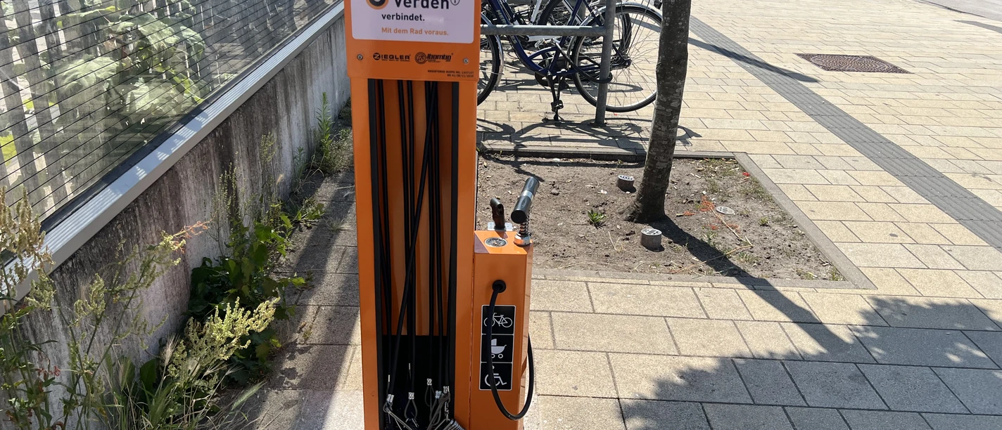 Fahrradstation Bahnhof Verden (4).jpeg Orange Fahrradreparaturstation mit Werkzeug und Luftpumpe am Bahnhof Verden.