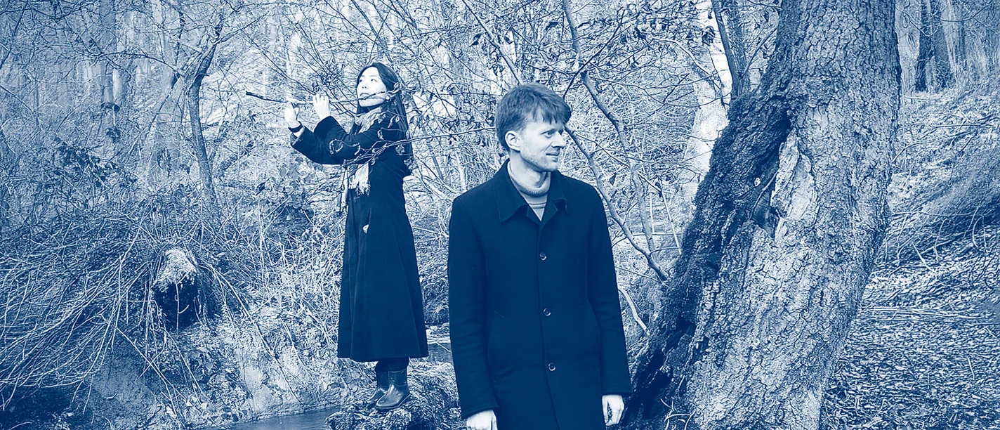 Pearl Huang and Melchior Kupke Blue-tinted duo portrait: a flutist and a musician by a stream in a wintry forest