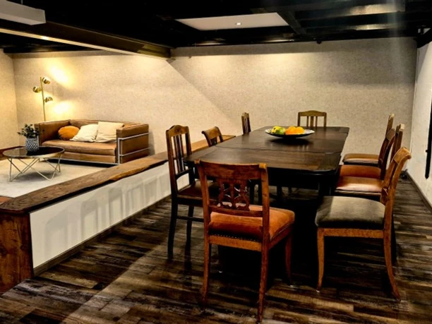 Meiers Mühle.jpg Essbereich mit dunklem Holztisch, Stühlen und angrenzender Sitzecke mit Ledersofa.