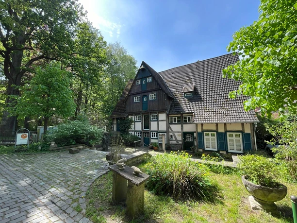 Meiers Mühle.jpeg Fachwerkhaus Meiers Mühle mit grünen Fensterläden und einem gepflasterten Vorplatz.