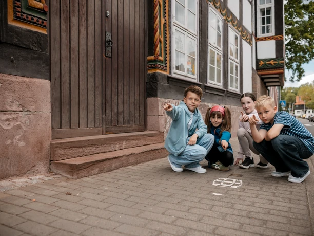 Vier Kinder entdecken eine Kreidemarkierung vor einem Fachwerkhaus in Einbeck.