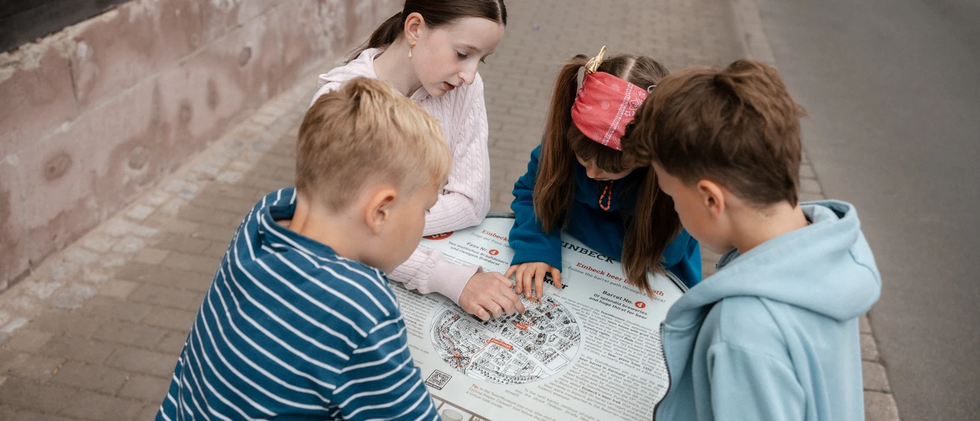 Vier Kinder lösen bei einer Stadtrallye in Einbeck Aufgaben an einer Infotafel.