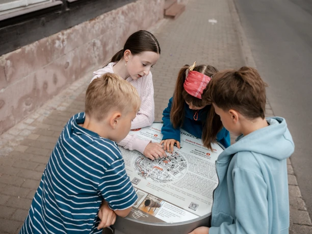 Vier Kinder lösen bei einer Stadtrallye in Einbeck Aufgaben an einer Infotafel.
