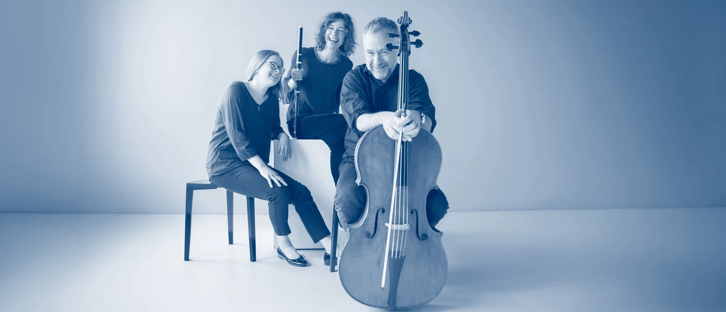 Trio Laflamme Drei lächelnde Musikerinnen und Musiker mit Traversflöte und Cello in blauem Studiolicht