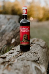 Schierker Feuerstein 0,7 Liter - auf einem Baumstamm Eine 0,7 Liter Flasche Schierker Feuerstein steht auf einem verwittertem Baumstamm vor unscharfer Naturkulisse.