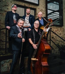 B.B. & The Blues Shacks posieren mit Mikrofon, Kontrabass und Gitarre vor Backsteinwand