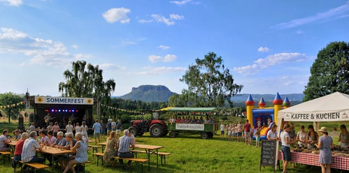 sommerfest Man sieht eine Wiese mit fröhlichen Menschen, die feiern