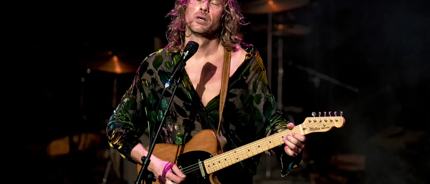Ralph de Jongh.jpg Ralph de Jongh singt auf der Bühne und spielt E-Gitarre im Scheinwerferlicht.