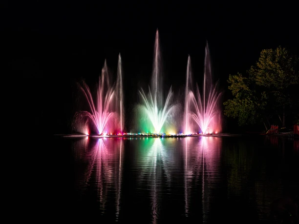2025_Seefest-Behringen (4).jpg Bunte Wasserfontänen leuchten nachts über dem Brunausee in Behringen und spiegeln sich im Wasser.