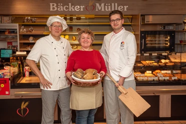 Bäckerei Müller Drei Mitarbeitende von Bäcker Müller stehen mit Brotkorb vor der Ladentheke.