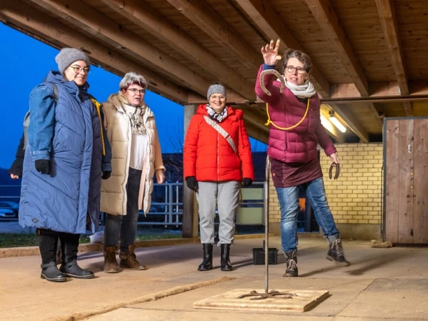Vier Frauen spielen bei winterlicher Abendstimmung Ringwerfen auf dem Bio-Hof Burgrain