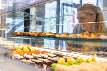 Frau betrachtet Kuchen in Vitrine