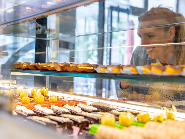 RheinMain Offenbach - Glykomania-Konditorei Frau betrachtet Kuchen in Vitrine