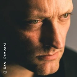 Nahaufnahme eines Mannes mit ernstem Blick, warmem Licht und dunklem Hintergrund