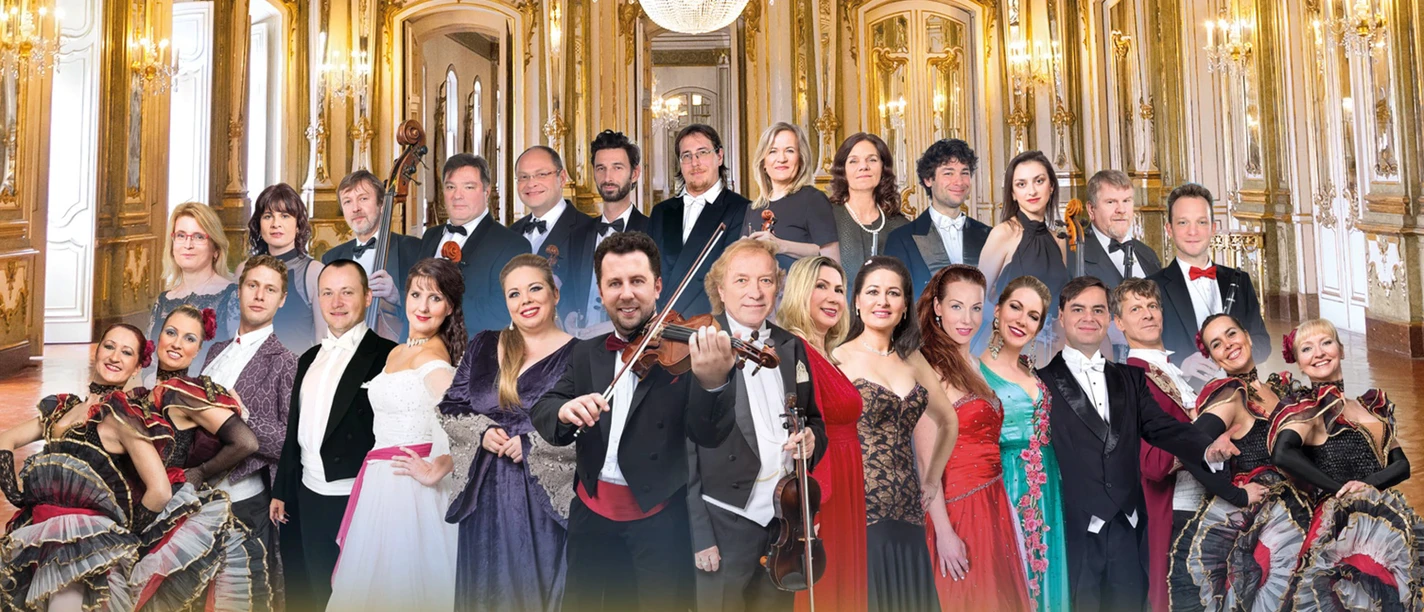 Ensemble der Richard Strauß Gala in festlicher Abendkleidung mit Instrumenten und Tänzer:innen in einem eleganten Spiegelsaal