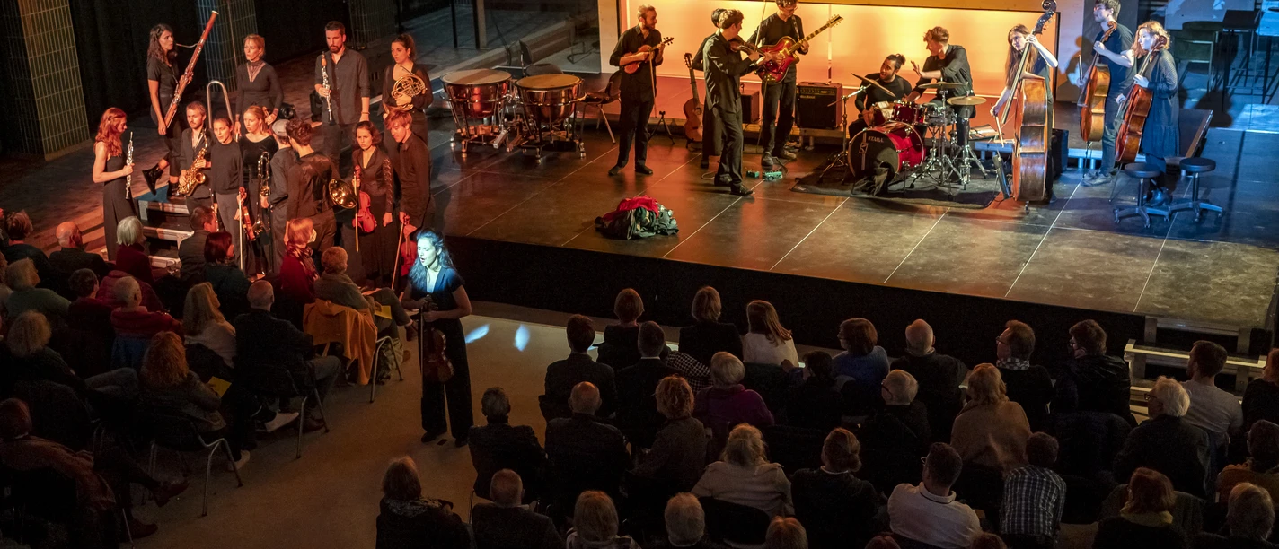 Kasseler Musiktage Auf der Bühne stehen die Musiker, vor der Bühne sitzen die Zuschauer.