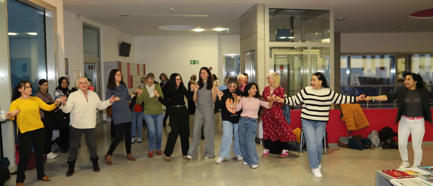 Hand in Hand Frauen tanzen Hand in Hand bei der Veranstaltung Frauen*Kraft im Medienhaus.