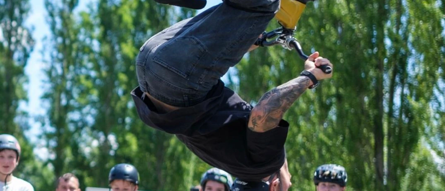 Marc Diekmann.jpg A BMX rider wearing a helmet performs a backward somersault in front of an audience at the pump track.