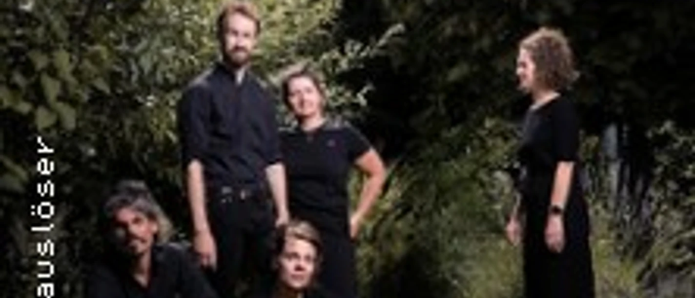 Fünf Personen in schwarzer Kleidung stehen und sitzen im Grünen.