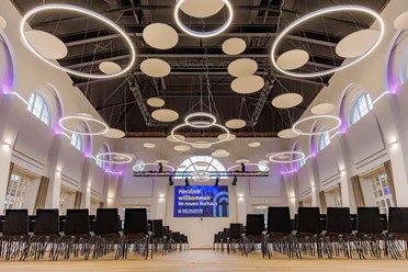 Galasaal im Kurhaus Bad Salzuflen mit Stuhlreihen, Rundlichtern und violettem Akzentlicht
