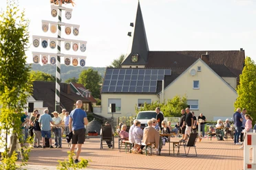 Menschen bei einer Zusammenkunft auf dem Dorfplatz Hüllhorst vor einer Kirche