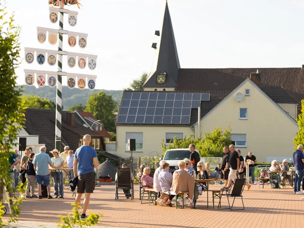 Menschen bei einer Zusammenkunft auf dem Dorfplatz Hüllhorst vor einer Kirche