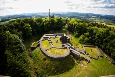 Luftaufnahme des Eisenbergs bei Korbach mit Burgruine und Georg-Viktor-Turm auf dem bewaldeten Gipfel, umgeben von der Korbacher Hochfläche und der Berglandschaft des Sauerlands
