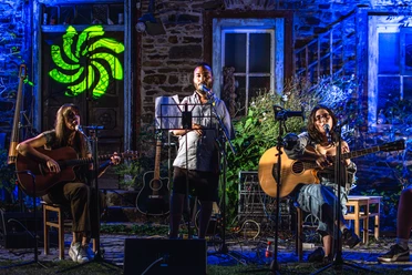 'All Inkl.' Drei Mitglieder von All Inkl. singen und spielen Gitarren bei blau beleuchtetem Auftritt