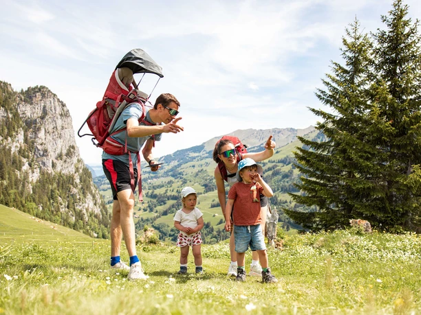 Treasure Hunt for the whole Family Parents with two young children are standing in hiking clothes on an alpine meadow