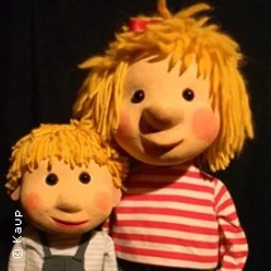 Zwei blonde Puppenfiguren, eine mit rot-weiß gestreiftem Shirt, vor schwarzem Hintergrund
