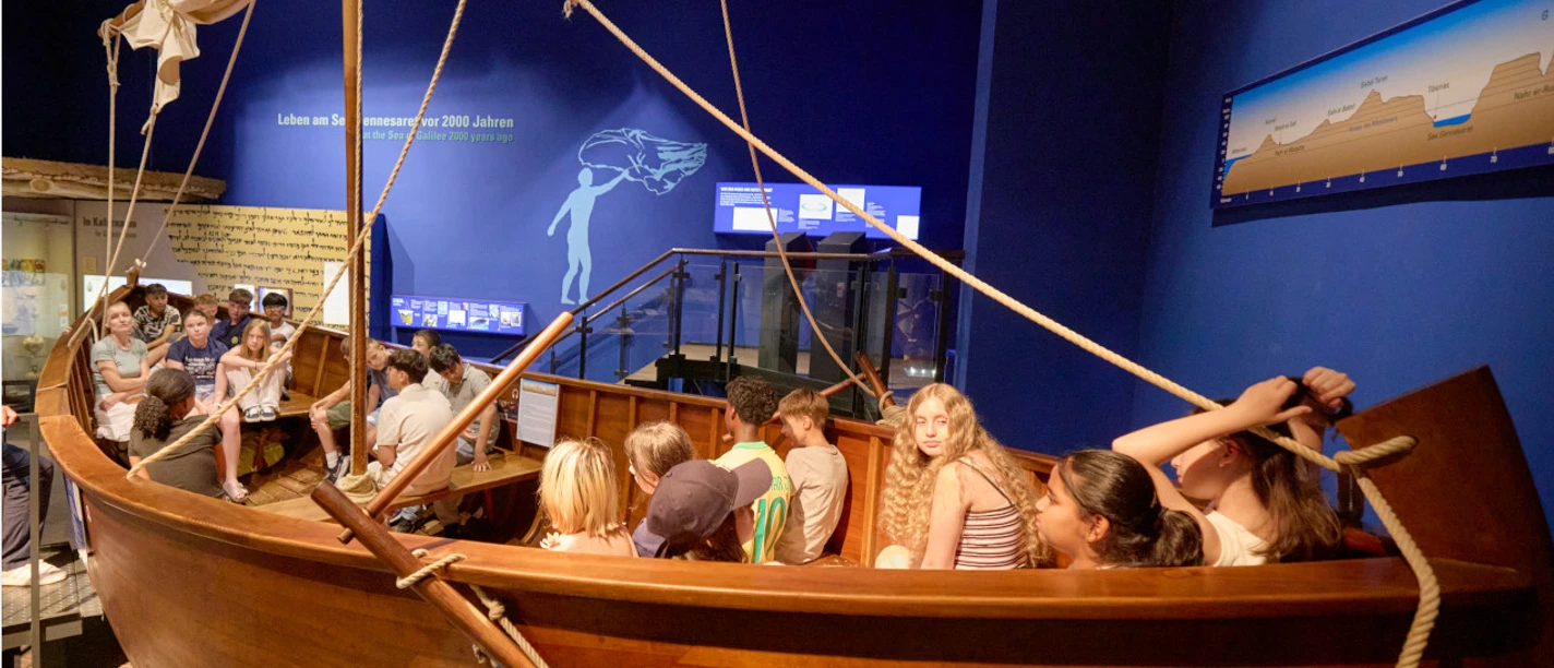 BIMU - Boot Kinder sitzen in einem Holzboot in einer Museumsausstellung
