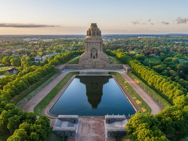 Drohnenaufnahme vom Völkerschlachtdenkmal und dem See der Tränen bei Sonnenaufgang im Sommer