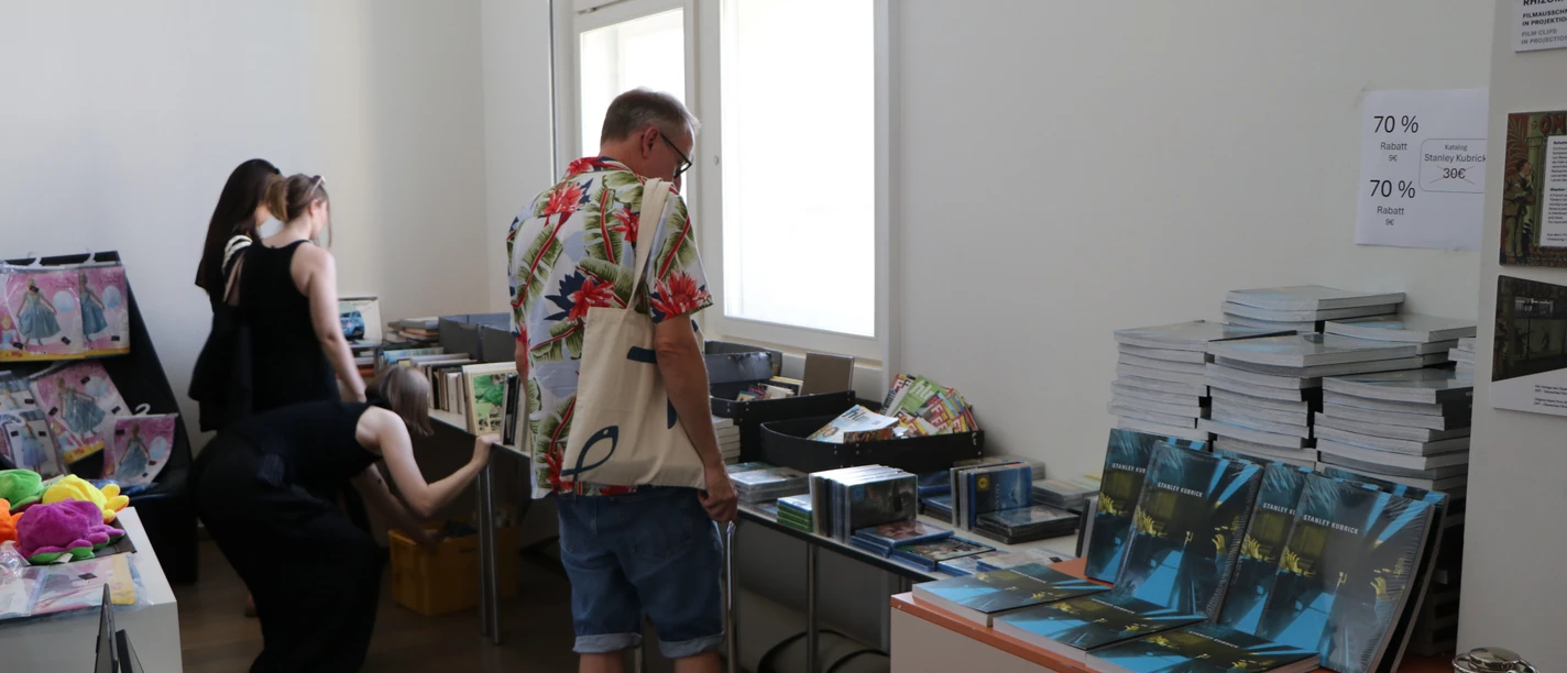 Besucher stöbern bei Bücherflohmarkt mit Büchern und Filmen