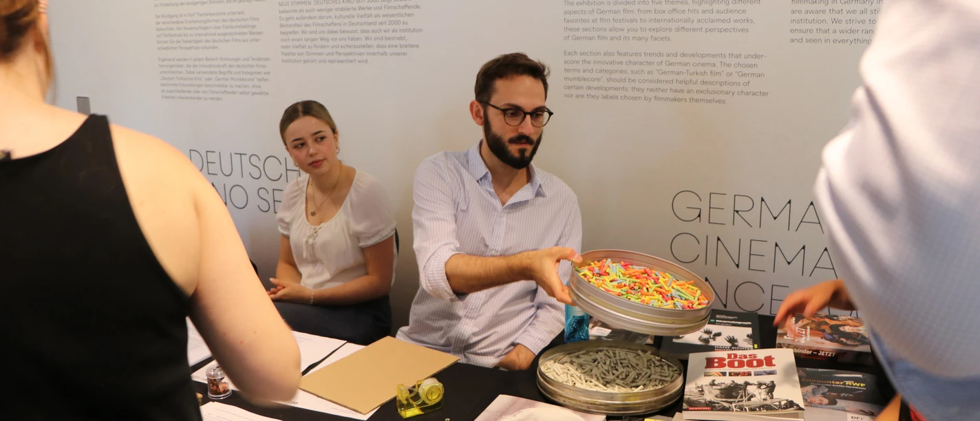 DFF - Ausstellungsquiz Personen an einem Tisch mit Filmheften und Ausstellungsquiz