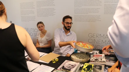 DFF - Exhibition Quiz People at a table with film brochures and an exhibition quiz