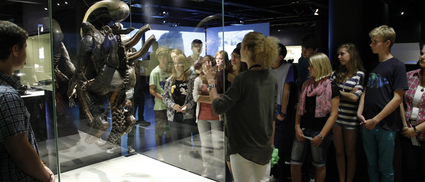 DFF - Dauerausstellung Gruppe bei Führung vor Alien-Figur in Museumsvitrine