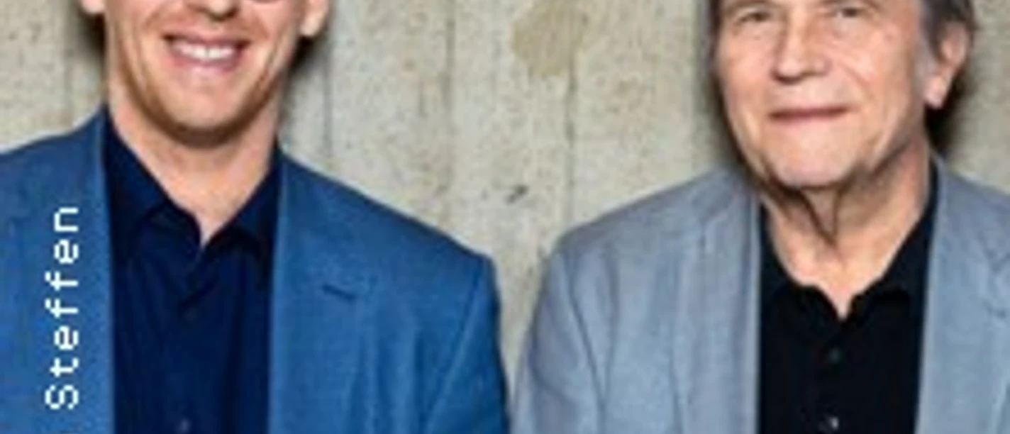 Porträt von Sebastian Kurtenbach und Rolf Heinze vor grauer Betonwand