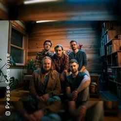 Fünf Musiker von Tophouse with Raynes in einem warm beleuchteten Raum
