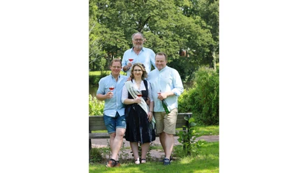 Vier Personen mit Weingläsern posieren im Park für das Weinfest Munster.