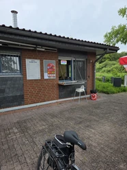Ankerplatz Hagenburg Ankerplatz Hagenburg. Gebäude mit geöffnetem Kioskfenster mit einem Hochstuhl und Preistafeln an der Wand