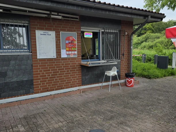 Ankerplatz Hagenburg Ankerplatz Hagenburg. Gebäude mit geöffnetem Kioskfenster mit einem Hochstuhl und Preistafeln an der Wand