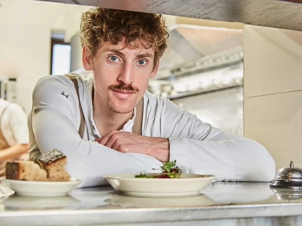 Bar Brio - Jakob Erdsiek Koch der Bar Brio am Pass mit angerichteten Tellern und Serviceklingel
