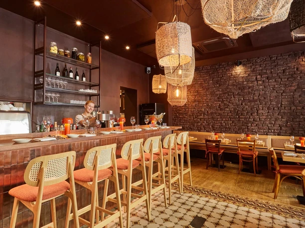 Bar Brio - Innenraum Innenraum der Bar Brio mit Tresen, gedeckten Tischen und warm leuchtenden Korblampen