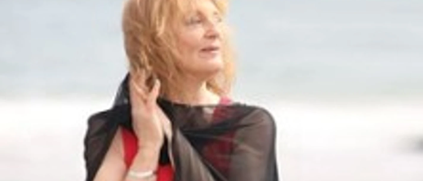 Porträt von Judy Niemack mit blondem Haar am Meer, in schwarzem Oberteil