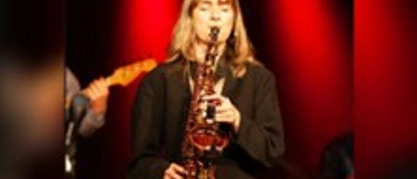 Musikerin mit Saxophon auf rot beleuchteter Bühne